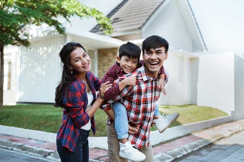 family smiling in front of home