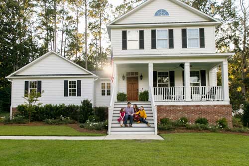 family sitting on steps of home